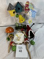 Photo of nested and grouped decorative garden and home items including birdhouses, ceramic mushrooms, garden stakes, and a ladybug decoration.