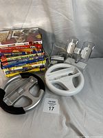 Photo of stack of DVDs and Nintendo Wii accessories arranged on white fabric background.