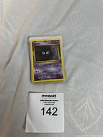 Stack of Pokémon cards featuring Gastly on top, placed on a white cloth surface with a MaxSold auction label visible.