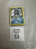 Stack of Pokémon cards with Poliwhirl card on top next to auction lot number