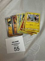 Photo showing a small stack of Pokémon cards with visible characters Charizard, Shinx, Poochyena, and Energy Search card on top