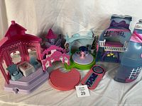 Photo of seven small colorful plastic toy playsets and accessories, including gazebos, benches, platforms, and slides in pastel pink, purple, aqua, and blue.