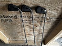 Three Lynx Tigress Elegance golf irons numbered 7, 8, and S with black protective head covers, laid against a wooden textured background.