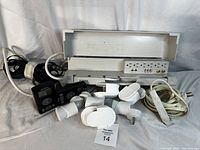 Assorted power bar, extension cords, adapters, and remote controls showing all items in the lot