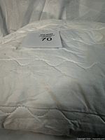 Close-up of queen mattress protector surface showing quilted diamond pattern and some stains.