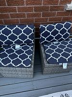 Two outdoor chairs with blue and white trellis pattern cushions seen from the front.