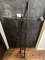 Front view of the tall shower organizer with four black metal wire baskets supported by a vertical frame.