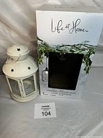 White metal tea light holder with glass panes and star cutouts beside boxed solar hanging pendant light