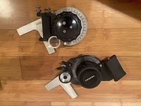 Top view of two drafting wheels: one Mutoh (black dial) and one Vemco (silver dial with magnifying glass) on wooden floor.
