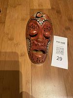 Top-down view of the carved wooden mask showing the facial features and painted details including abalone shell inlays.