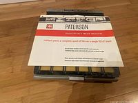 Top view of Paterson contact proof printer with attached instruction manual on wooden floor.