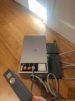 Side and top view of the Rollei projector showing the control panel, wired remote, and slide tray.