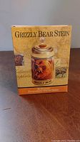 Front view of the stein in its original box showing 'Grizzly Bear Stein' text and design.