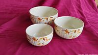 Three vintage Hall's bowls of 9, 7, and 6 inch sizes displayed on a pink fabric background.