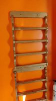 Full view of one wooden wall spice rack with five shelves against an orange wall.