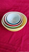 Nested listing of four Pyrex mixing bowls in primary colors: yellow, green, red, and blue.
