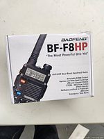Box with Baofeng BF-F8HP handheld radio branding and product information. Shows features such as selectable 8 watt output, VHF/UHF dual band, CTCSS/DCS tone codes, FM radio, flashlight, and emergency tone burst.