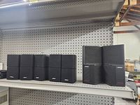 Front view of 10 Bose satellite speakers and 2 Acoustimass bass modules on shelf.