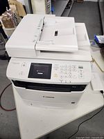 Front-left perspective showing automatic document feeder, paper output tray and control panel