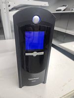 Front view showing the blue LCD screen and power button of the CyberPower UPS.