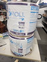 Two unopened rolls of Knauf EcoRoll R-13 Kraft insulation stacked, labeled for 2x4 walls.