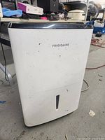 Front view of white Frigidaire dehumidifier showing brand logo and water level window with some dirt marks.