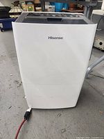 Front view of white Hisense dehumidifier on floor with power cord attached
