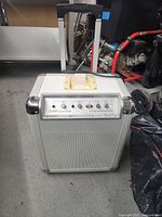 Front view of Ion Block Rocker portable speaker unit on floor showing speaker grill, control panel with knobs, switches and iPod dock.