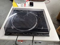 Full view of JVC AL-F3 turntable with clear dust cover and power cord on white table.