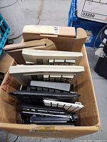 Box filled with multiple computer keyboards in various colors stacked vertically.