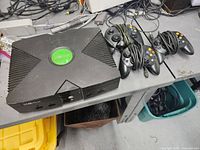 Top view of Xbox console and three wired controllers on table.