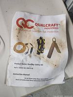Instruction manual cover showing Qualcraft Industries brand and rooftop safety kit components (harness, rope, anchor)