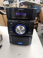 Front view of Sony Mini HiFi Component System showing display screen, control buttons, and CD tray.