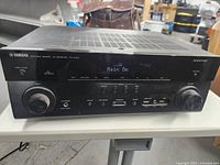 Front view of Yamaha AV receiver powered on, displaying 'Main On' on screen.