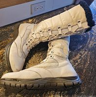 Side view of the pair of white Blondo winter boots size 9.5, showing the lace-up front, quilted shaft, fur trim, and rubber sole.