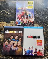 Photo showing three boxed DVD sets of The Big Bang Theory TV series in new condition.