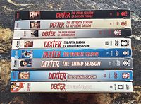 Photo of a stack of eight Dexter TV series DVD box sets arranged in order from first to final season.