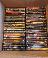 Photo showing stacked DVDs with titles including The Thing, Pan's Room, The Last Exorcism, Hellraiser, Insidious, Firequake, and various other horror movies.