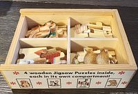 Wooden box with compartments containing wooden puzzle pieces. The front of the box shows graphics indicating there are 4 wooden jigsaw puzzles inside, each in its own compartment.