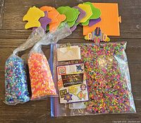 Photo shows multiple bags of colorful Perler beads, pegboards of various shapes and colors, a small bead design butterfly, and an instruction booklet.