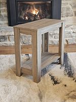 Full view of wooden console table placed near fireplace, showing the entire piece including legs and shelf.