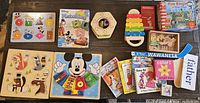 Photo showing assortment of wooden puzzles, xylophone, and several small children's books and learning cards.