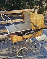 Side view of vintage pram showing yellow-brown fabric and chrome handlebar.