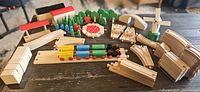 Full set of wooden train pieces displayed on table including trains, track pieces, trees, and accessories