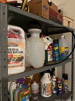 Shelf with multiple pest control and weed killer products including liquid containers, aerosol cans, and pump sprayers