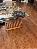 Overview of the coffee table showing the glass top with items on it and the wooden slatted base underneath.