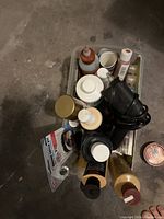 Top view of assorted bottles, liquids and heat tool packed inside a transparent plastic bin