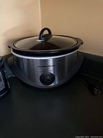 Photo of the Crockpot showing the stainless steel exterior, control knob and glass lid with handle.
