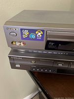 Sony VHS VCR and Samsung DVD player stacked on a table, showing front panels and brand logos.