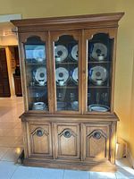 Full view of wooden china cabinet with three upper glass doors displaying china and glassware (not included) and four lower wooden paneled storage doors.